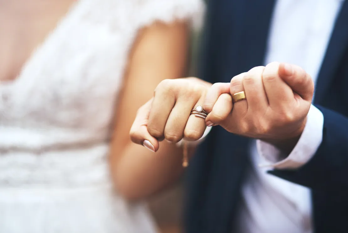 Newlywed couple doing a pinky swear gesture on their wedding day