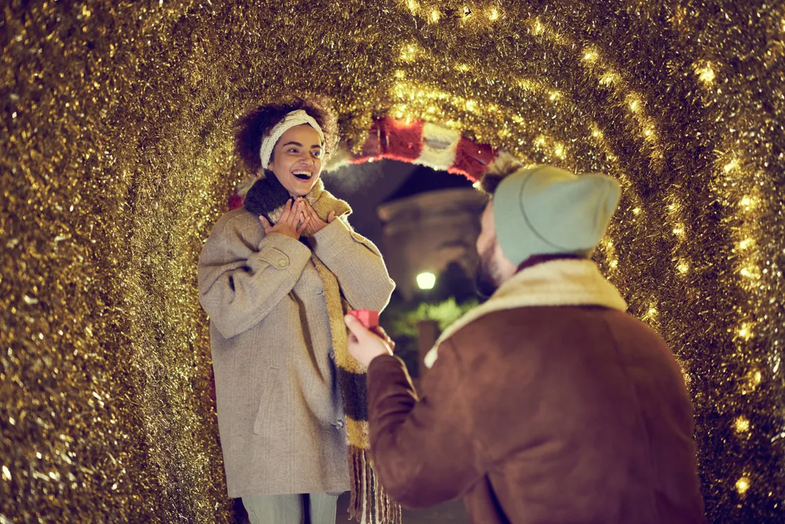 Man Proposing To A Woman Under Fairy Lights