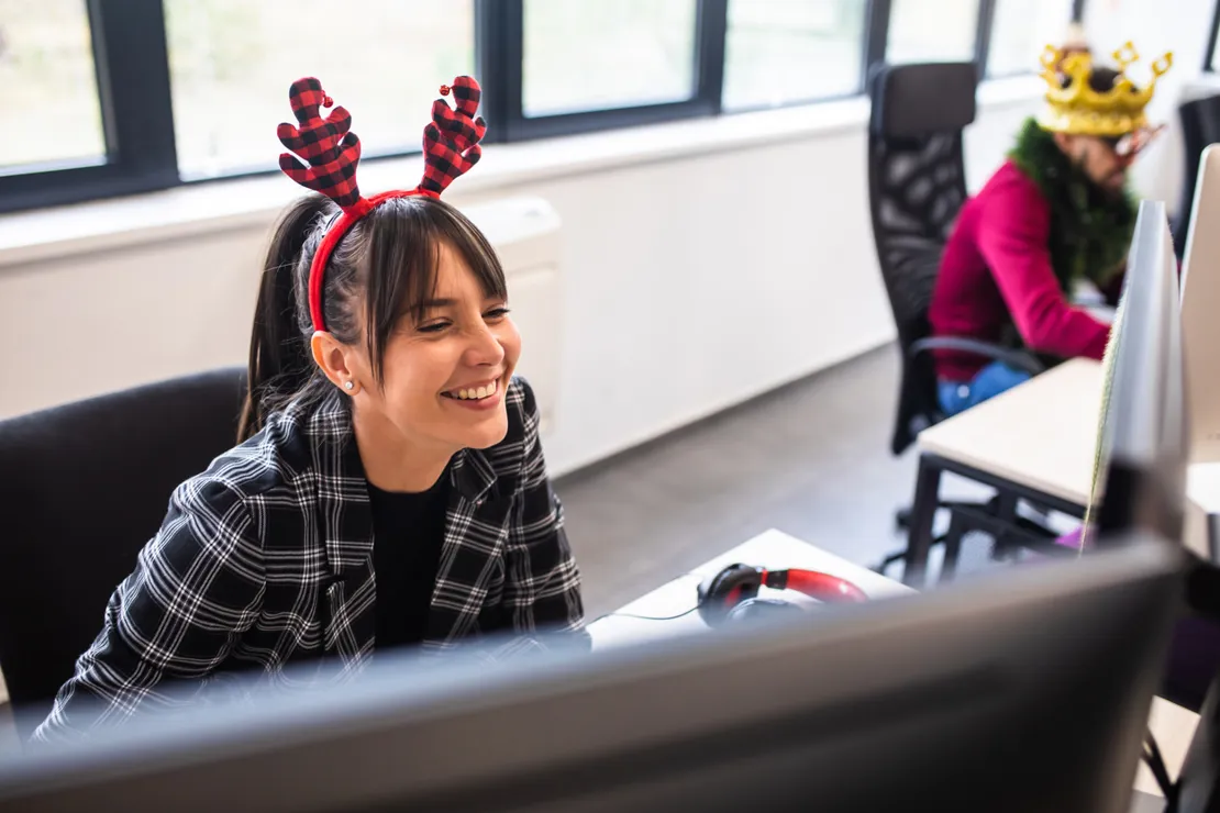 Woman At Desk In Reindeer Antlers Laughing