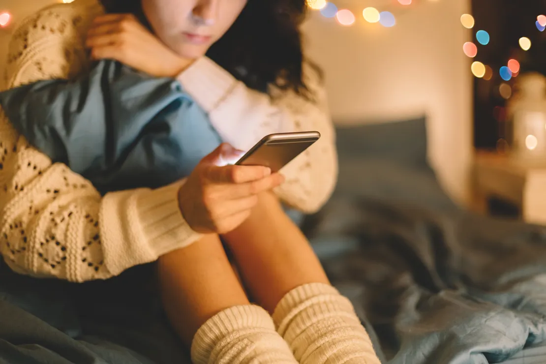 Romance Scam Woman In Bed Looking At Phone