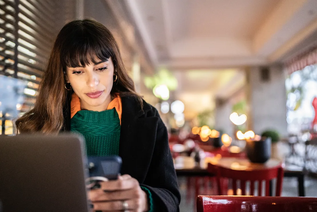 Businesswoman Working In A Cafe Looking At Her Phone