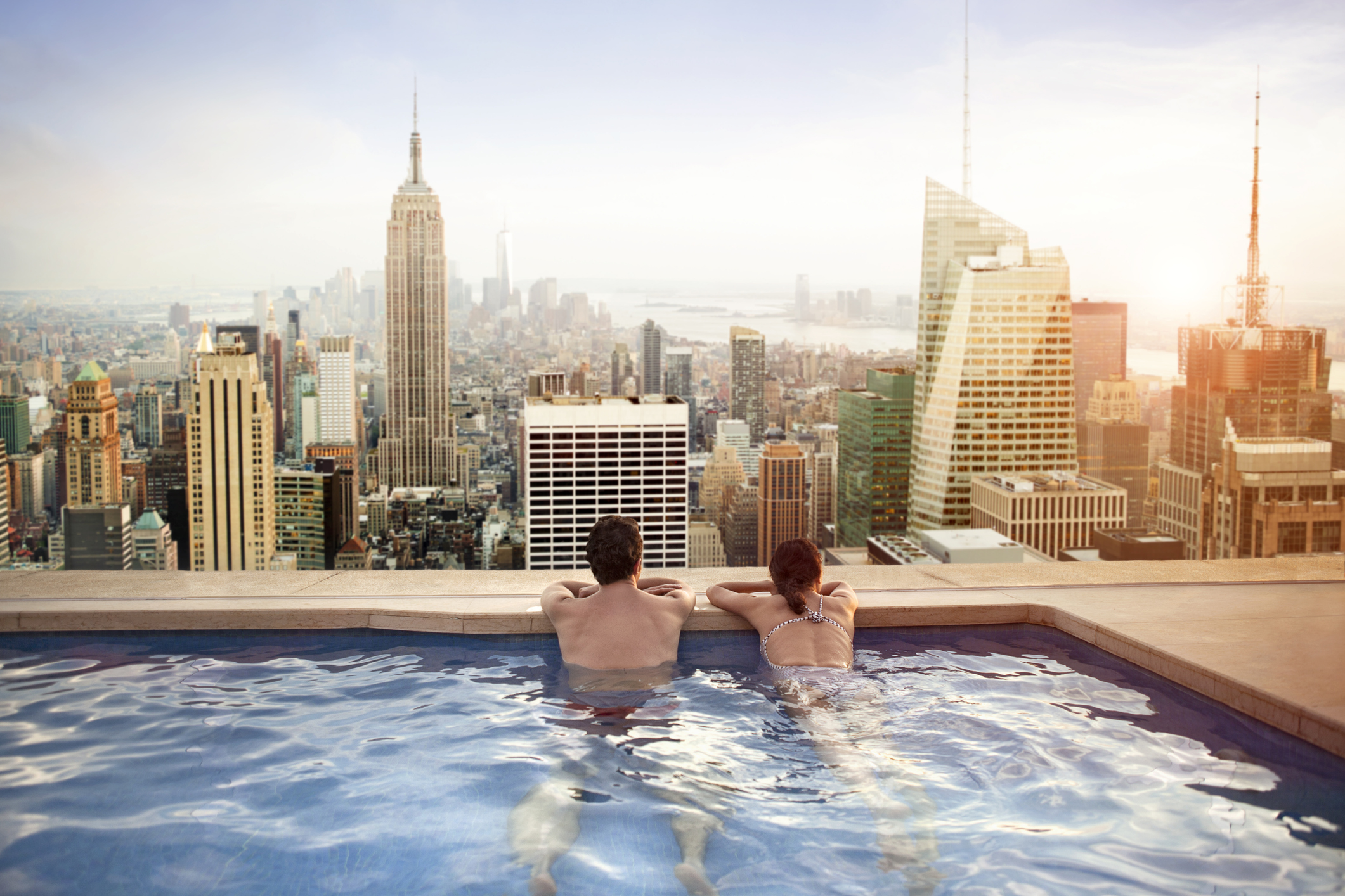 Couple Swimming Overlooking The City On Luxury Holiday
